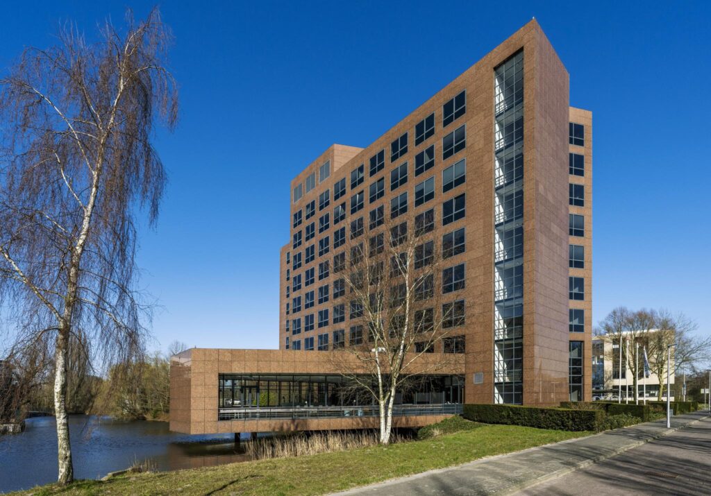 Modern office building on Prof. W.H. Keesomlaan next to a canal under a clear blue sky.